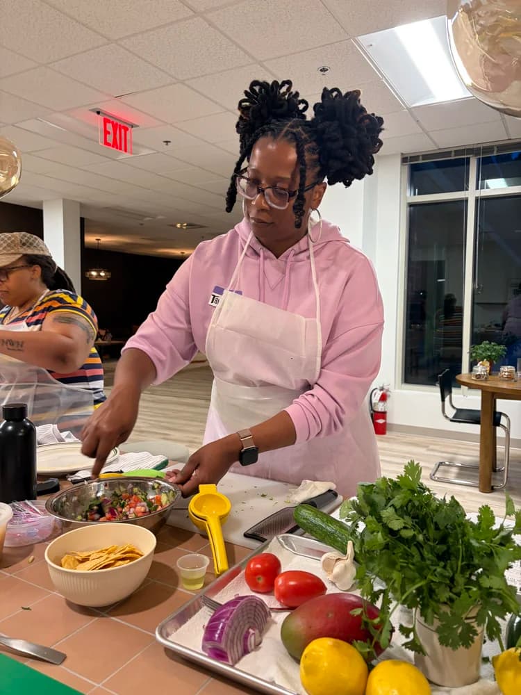 An adult participant prepares fresh ingredients in the Kind Kitchen classroom