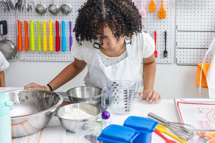 A young cook experiments with ingredients and measuring tools