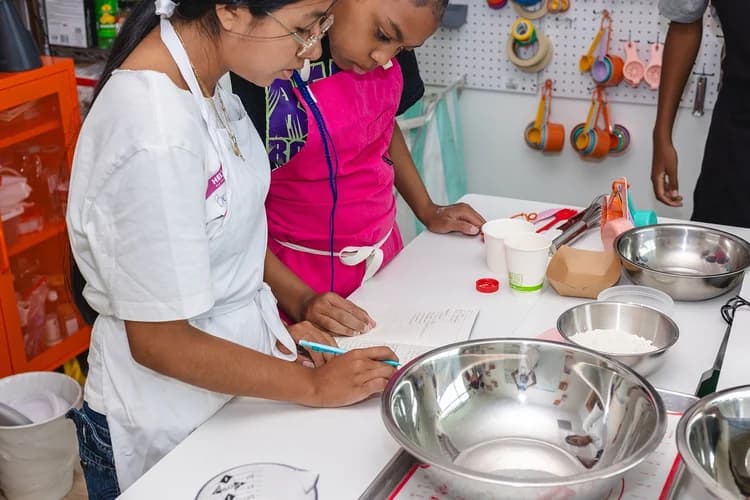Two young cooks review a recipe together at a kitchen worktable